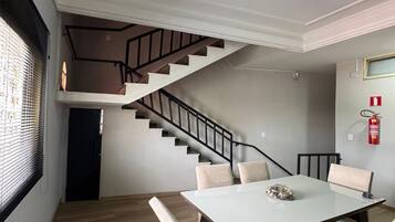 A dining area with a table and chairs, a staircase, and a fire extinguisher on the wall.