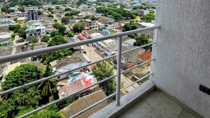 Un balcon offrant une vue sur le paysage urbain, avec des bâtiments et de la verdure.