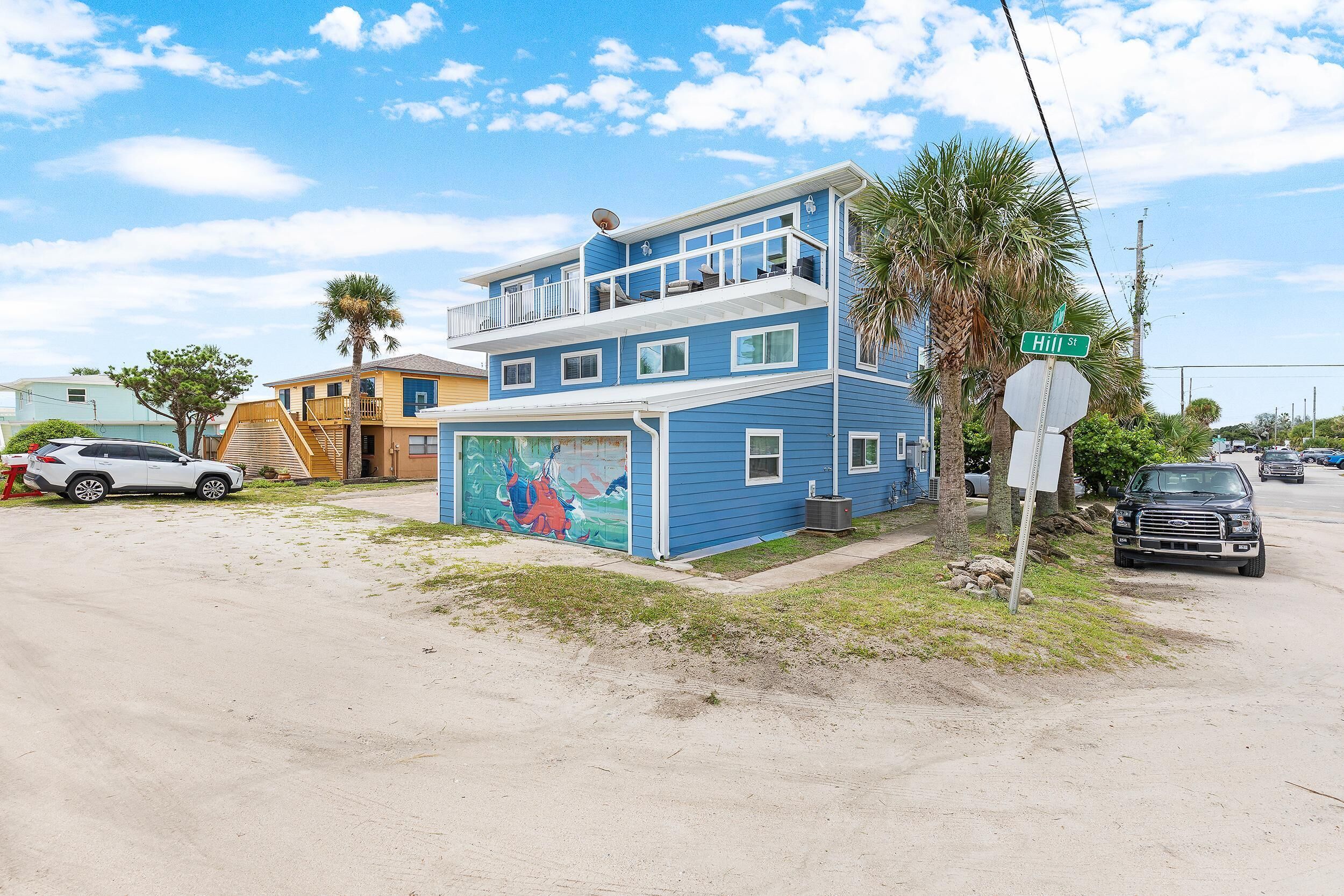A two-story building with a blue exterior, a balcony, and a mural on the lower level.