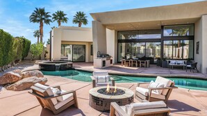 Un espace piscine extérieur moderne, doté de chaises longues, d’un foyer et d’un jacuzzi.