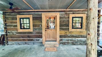 A log cabin with a wooden door, two windows, and a welcome mat.