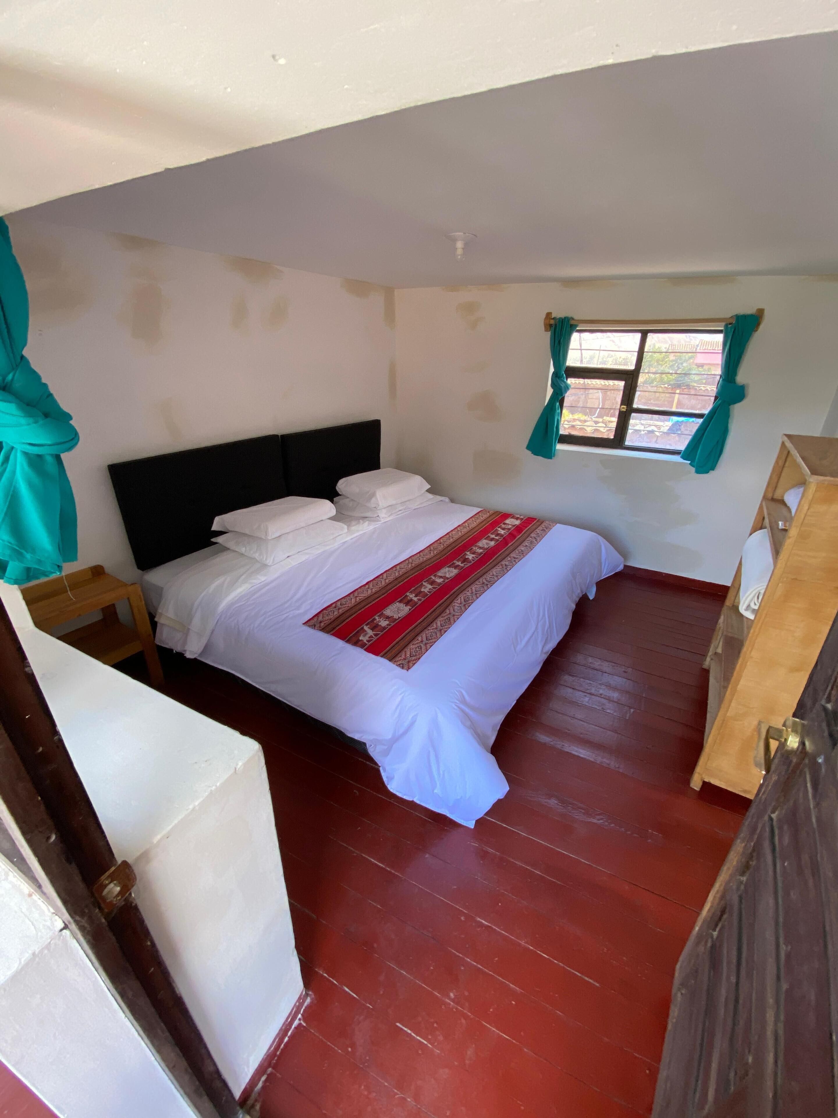 A bedroom with a bed, wooden nightstands, a wooden wardrobe, and a window with curtains.