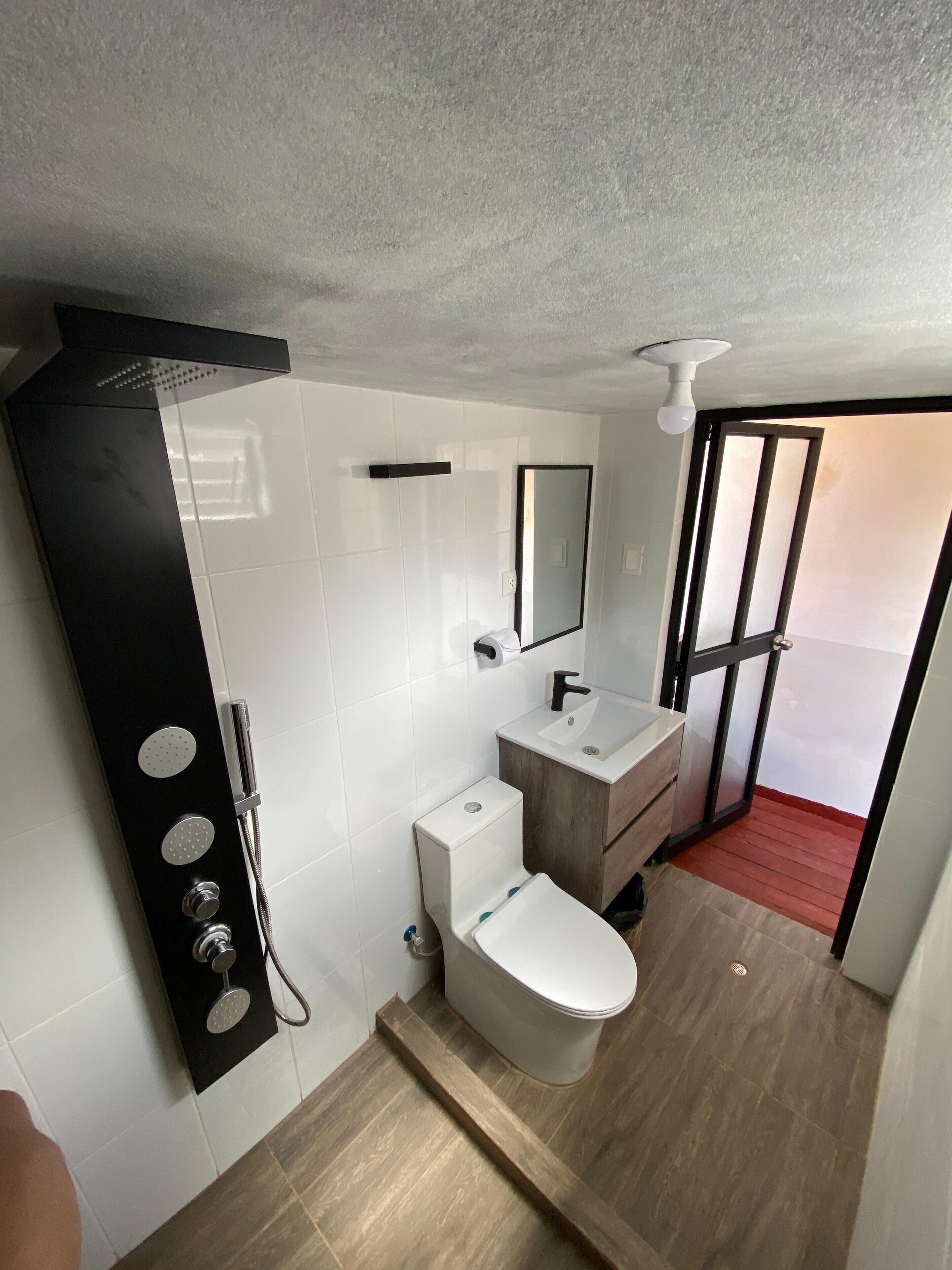 Un baño moderno con inodoro, lavamanos y ducha.