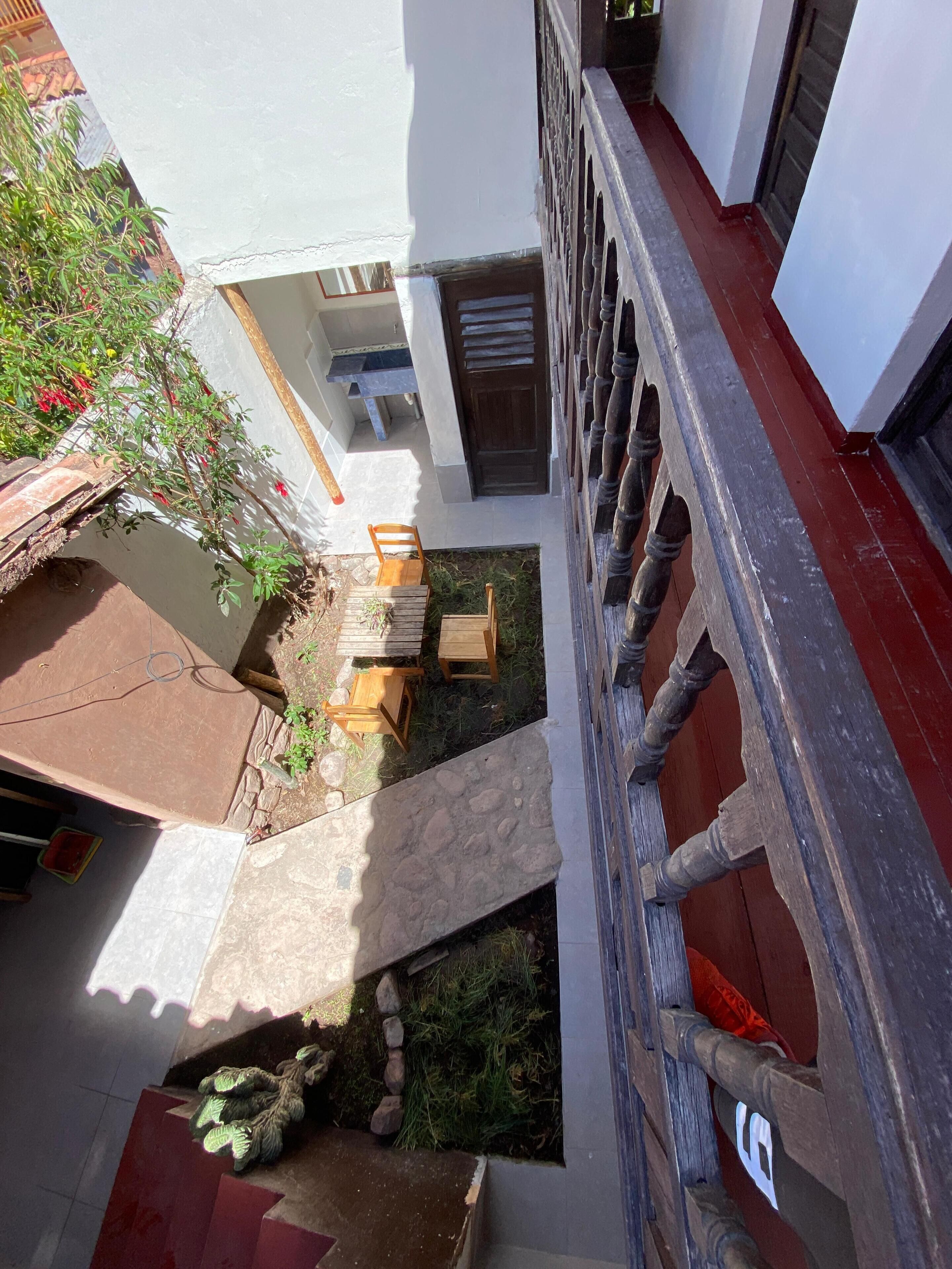 A courtyard with a stone pathway, wooden furniture, and a small garden area.