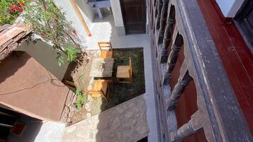 A courtyard with a stone pathway, wooden furniture, and a small garden area.