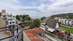 A coastal residential area with a mix of modern and traditional architecture, including a prominent building with a tiled roof and a smaller structure with a corrugated metal roof.