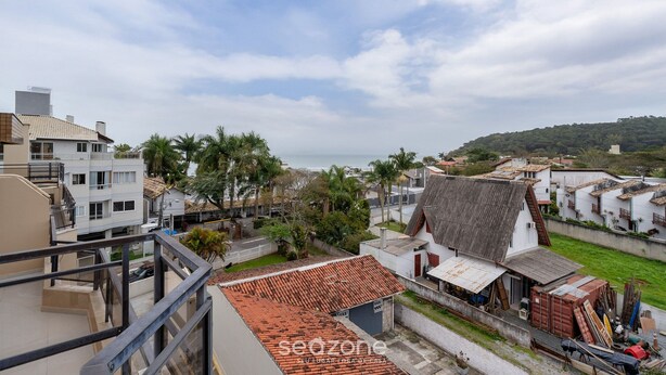 Zona residencial costera con una mezcla de arquitectura moderna y tradicional, incluyendo un edificio destacado con tejado de baldosas y una estructura más pequeña con tejado de chapa corrugada.
