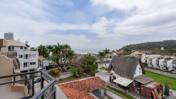 Zona residencial costera con una mezcla de arquitectura moderna y tradicional, incluyendo un edificio destacado con tejado de baldosas y una estructura más pequeña con tejado de chapa corrugada.