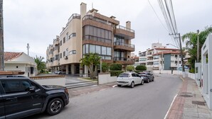 A multi-story residential building with balconies, a gated parking area, and a street view.