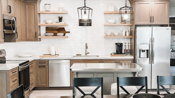 Een moderne keuken met houten kastjes, roestvrijstalen apparatuur en een centraal eiland met zitplaatsen.