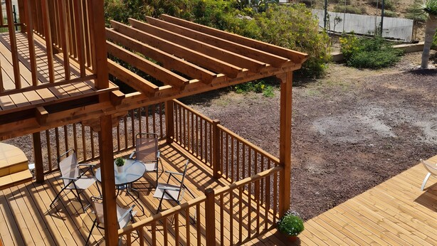 A wooden deck with outdoor furniture, a pergola, and a view of the landscape.