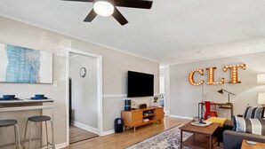 Een moderne woonkamer met een flatscreen televisie, een plafondventilator en een 'CLT' bord.