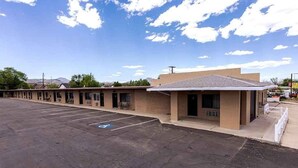 A motel with a parking lot and a single-story building with a flat roof. - Double Queen Bedroom_Western Themed_Bryce Canyon (Panguitch)