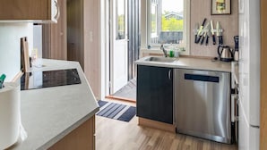Uma cozinha moderna com lava-louças embutida, uma pia e uma janela com vista para um jardim.