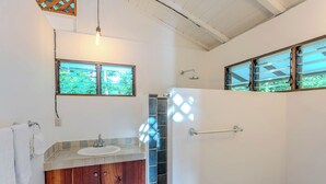 Une salle de bain avec un meuble-lavabo en bois, un lavabo blanc et une douche dotée d’une porte en verre.