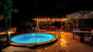 Une piscine entourée d’un patio, comprenant un espace salon couvert et du mobilier d’extérieur.