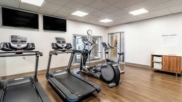 A fitness center with treadmills, elliptical machines, and a wall clock.