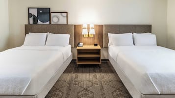 Ett hotellrum med två sängar, ett nattduksbord med en lampa och en matta med ett geometriskt mönster.
