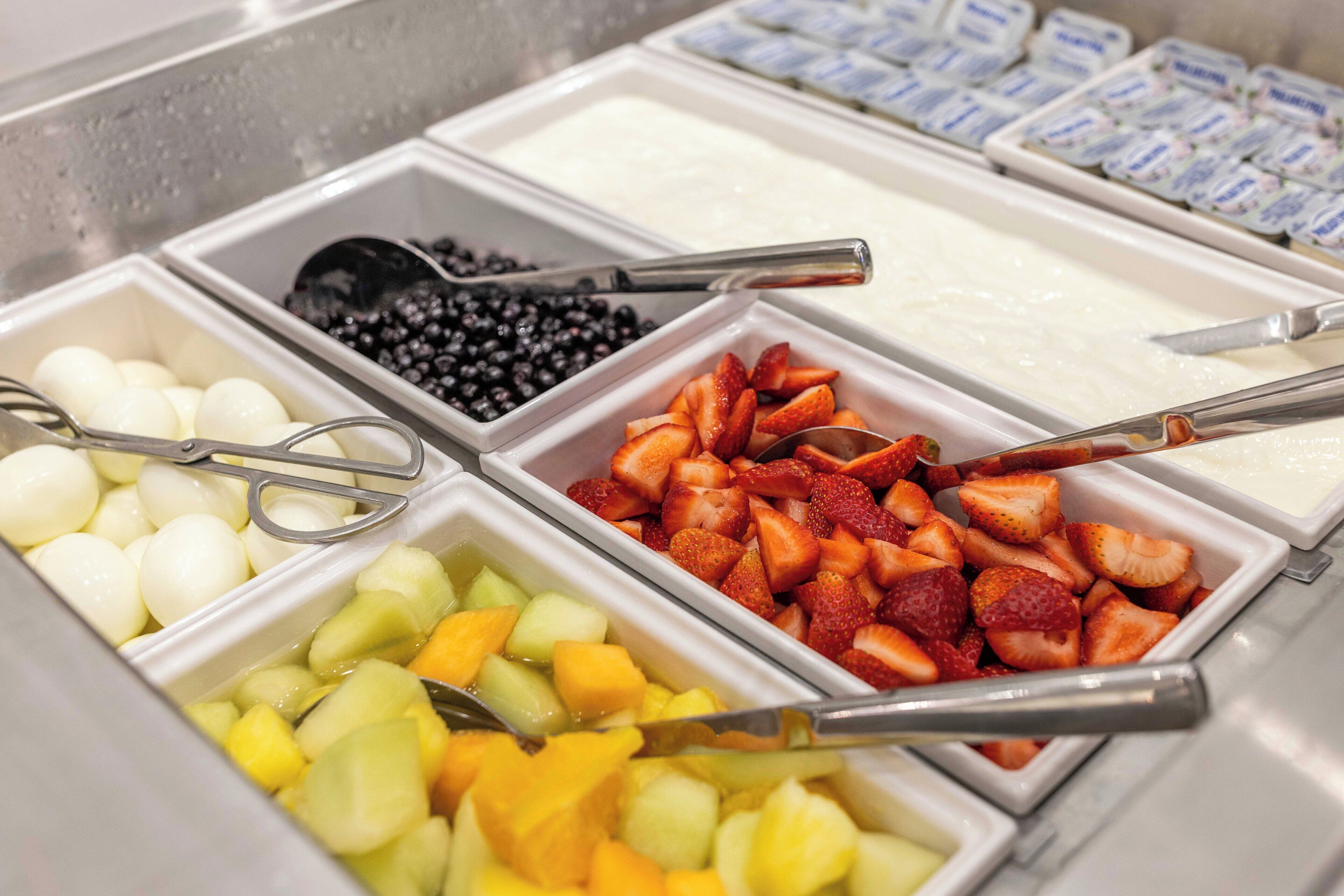 A buffet with various food items including fruits, yogurt, and eggs.