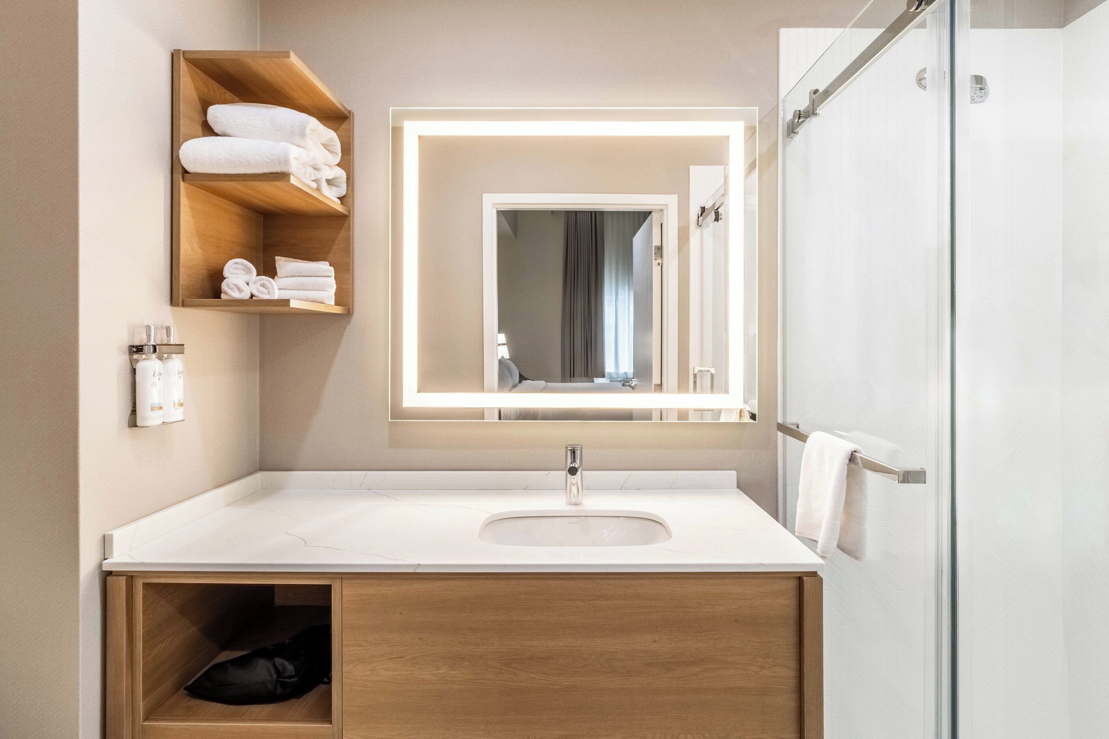 A modern bathroom with a white sink, a mirror, and a towel rack.