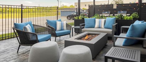 An outdoor patio area with wicker furniture, a fire pit, and a pergola.