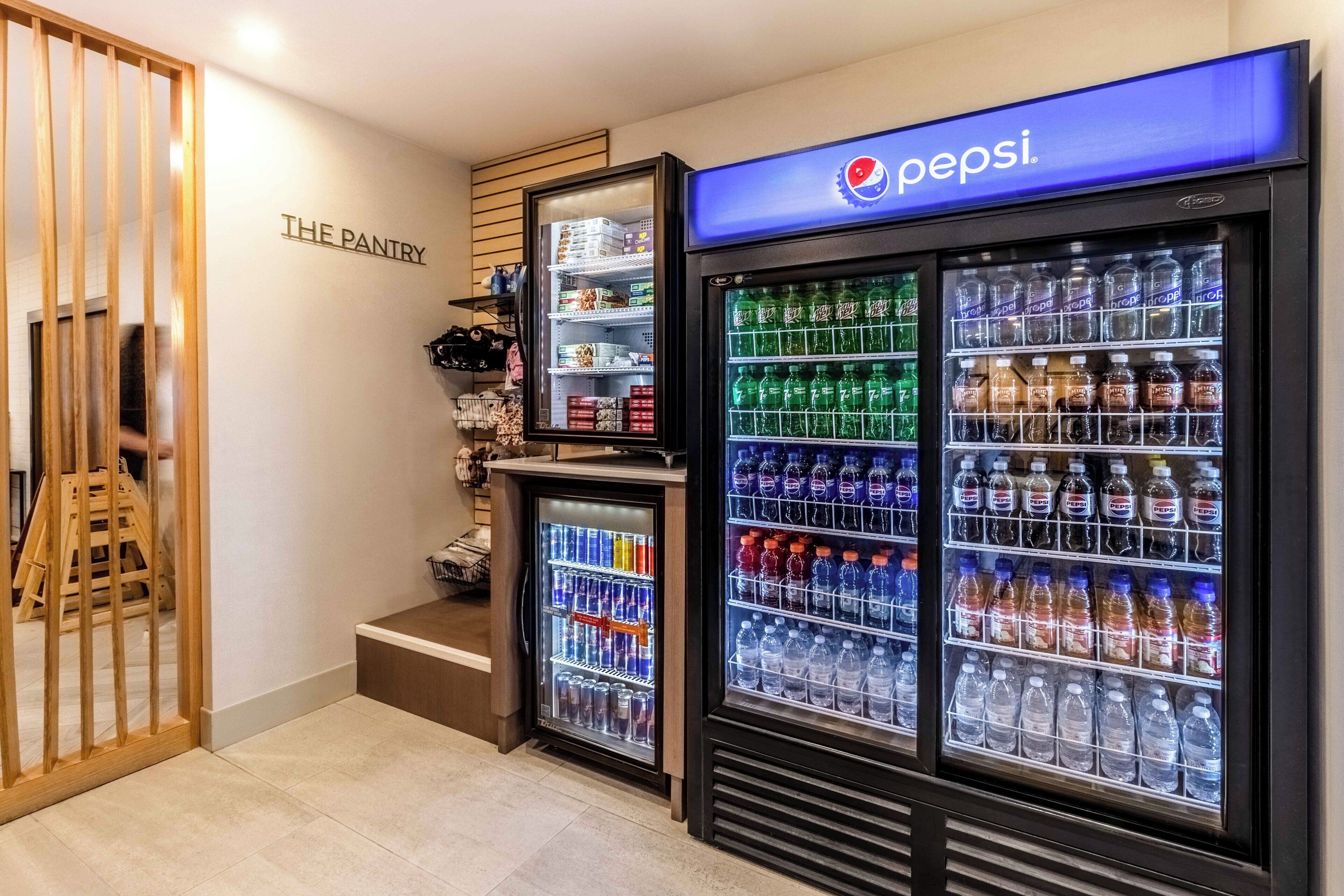 Zona de máquinas expendedoras con refrigeradores de Pepsi y una pequeña kitchenette identificada como 