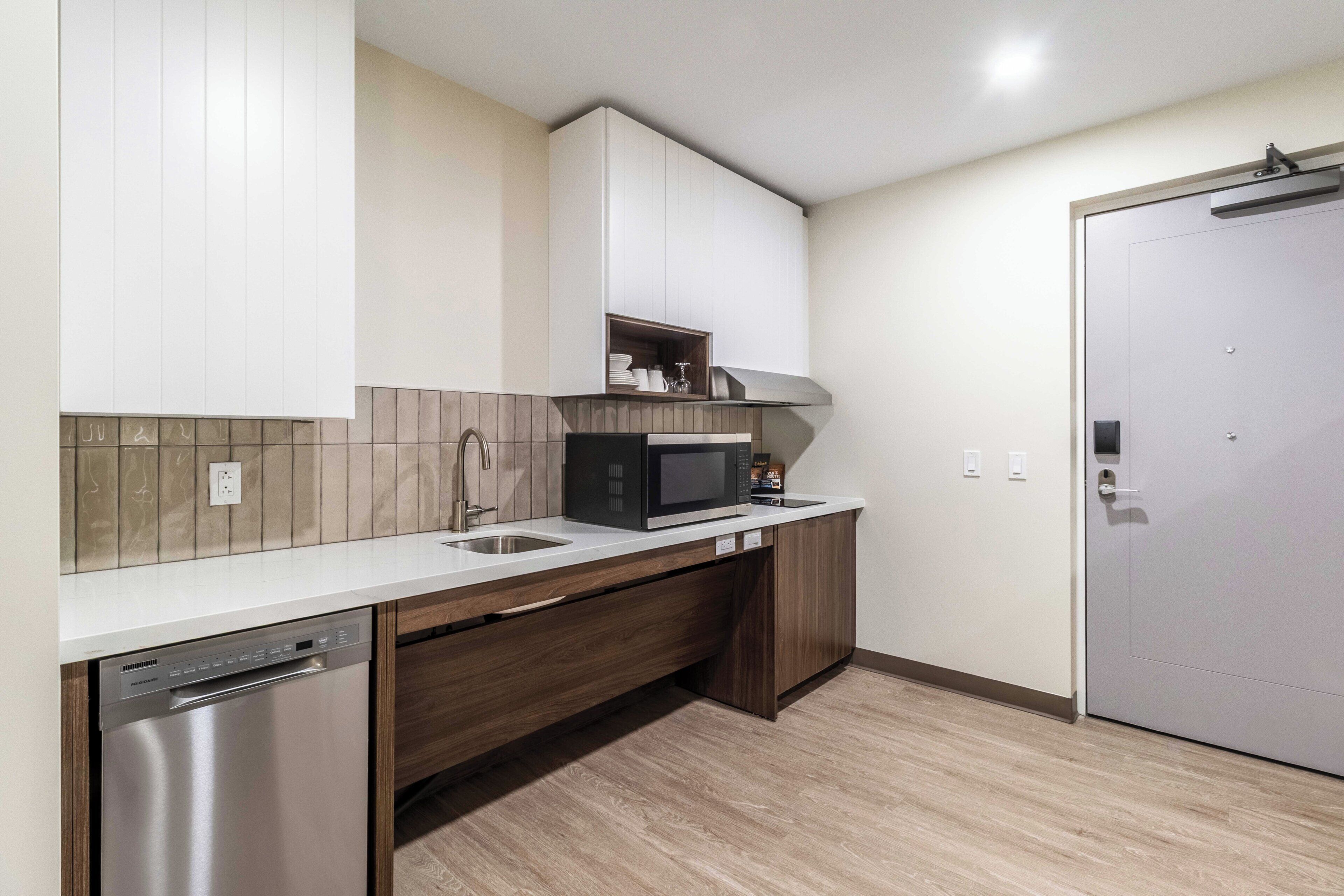 A modern kitchen with a dishwasher, microwave, and wooden cabinets.
