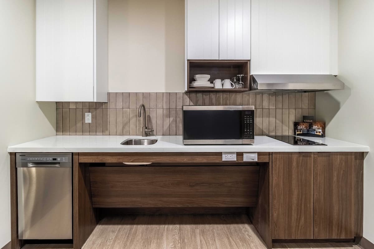 Una cocina compacta con lavavajillas, microondas y armarios de madera.