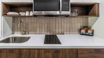 Een moderne keuken met een ingebouwde magnetron, een roestvrijstalen spoelbak en houten kastjes.