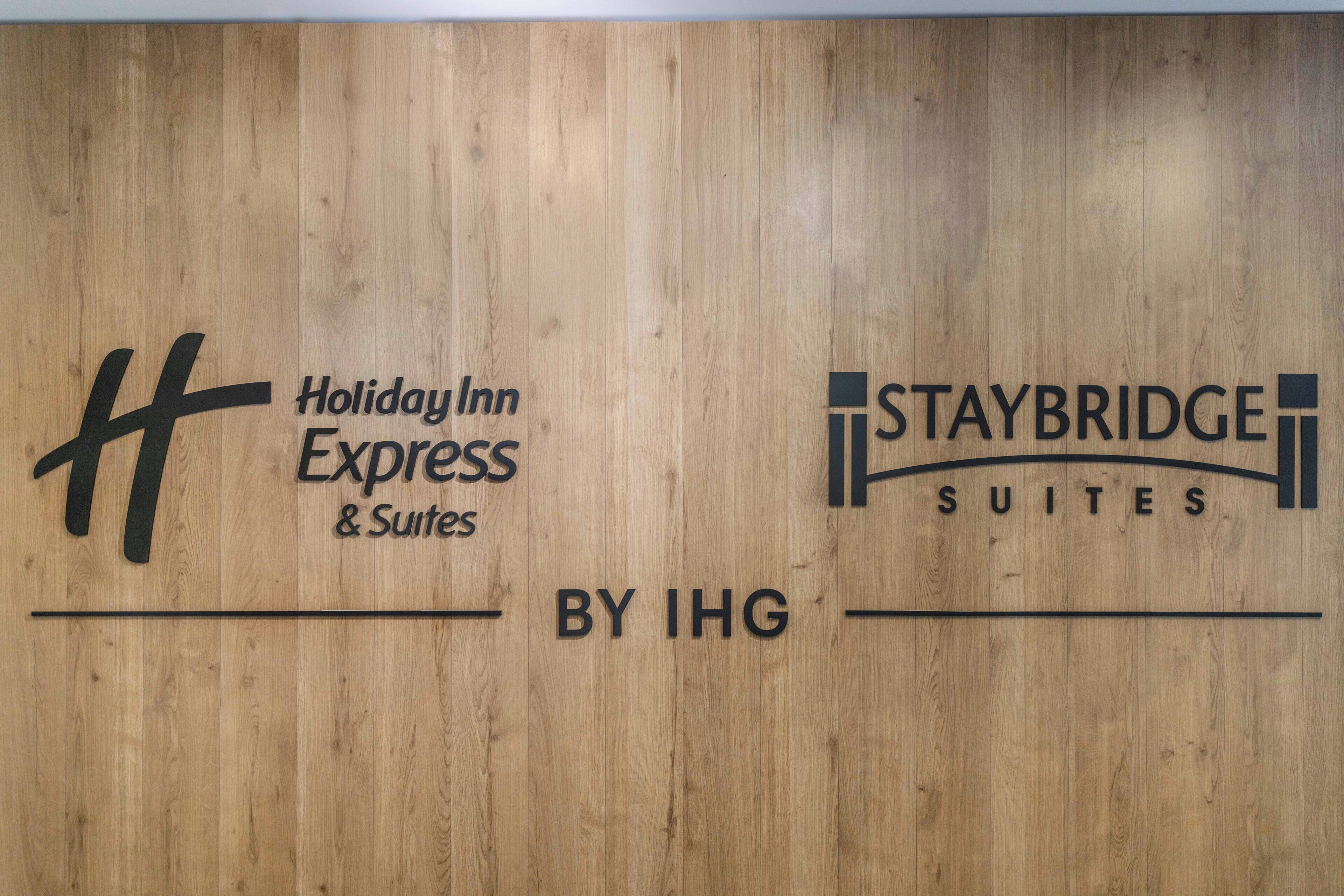 A wooden wall with logos for Holiday Inn Express & Suites and Staybridge Suites by IHG.