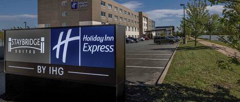 A Staybridge Suites Holiday Inn Express sign with a parking lot and a building in the background.