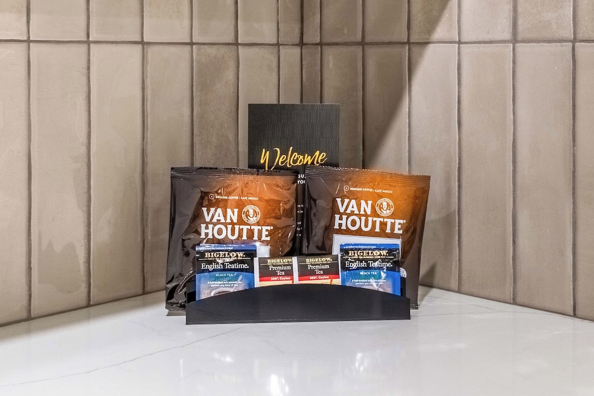 Un expositor con dos bolsas de Van Houtte English Tea Time y té Bigelow Premium, frente a una pared de azulejos.