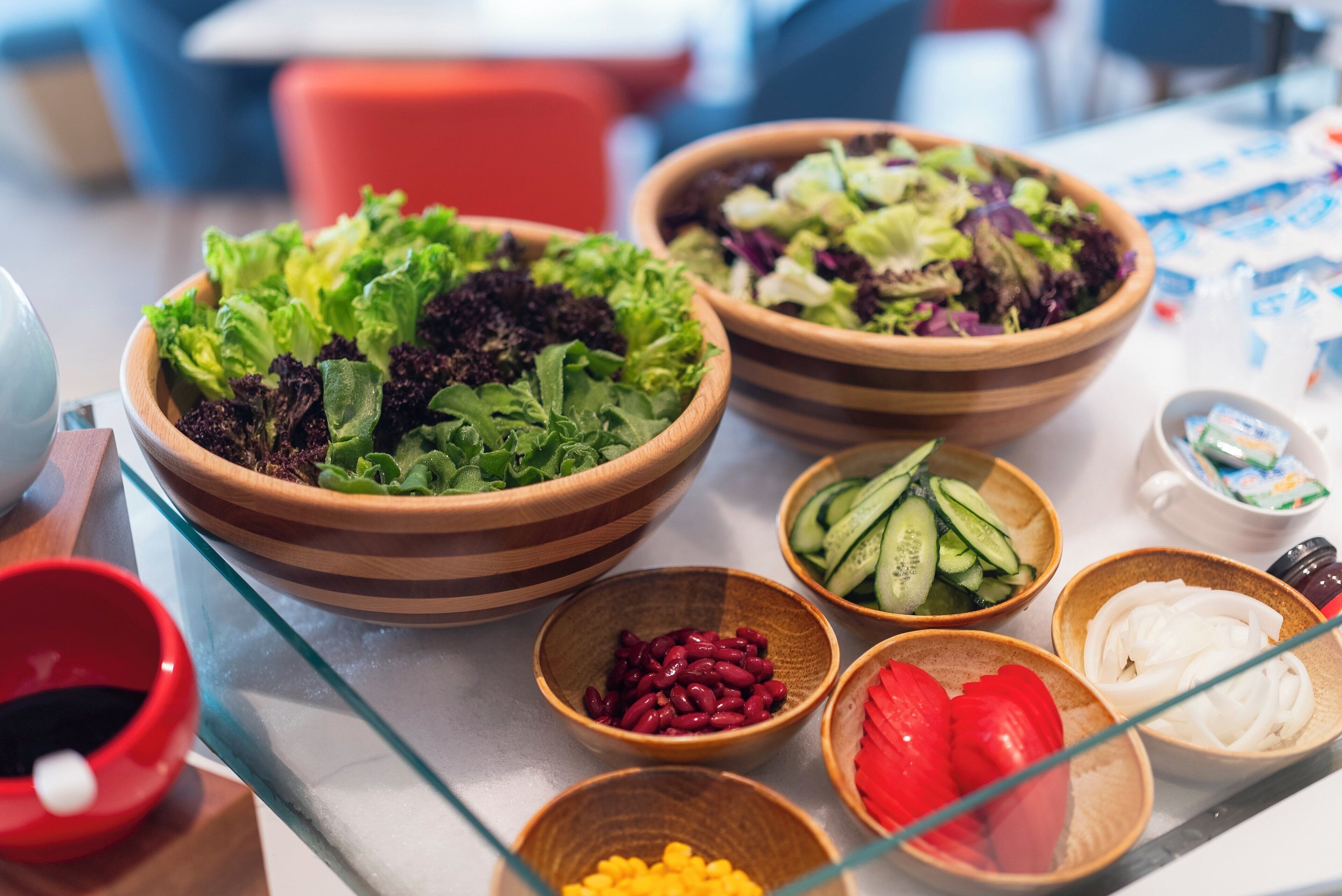 A table with various food items including bowls of salad, cucumbers, tomatoes, and beans.