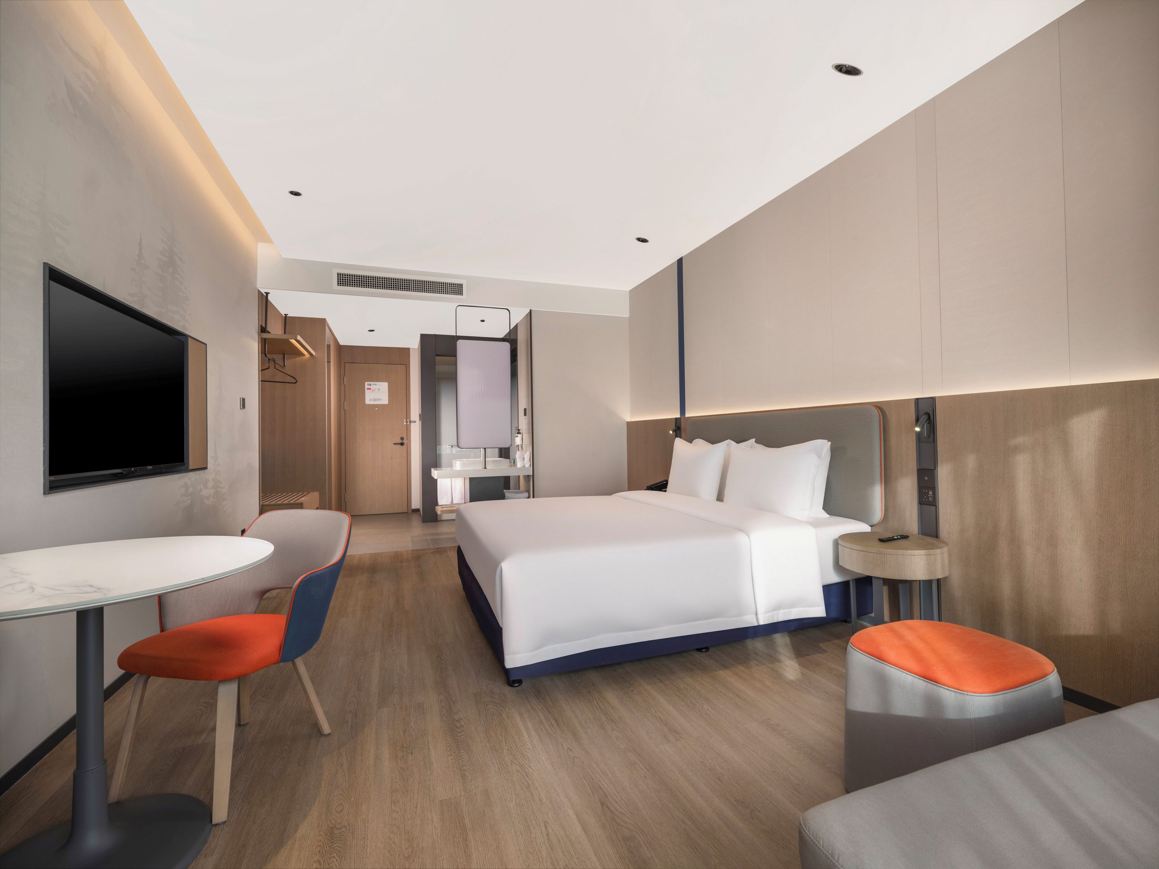 A modern hotel room with a large bed, a desk, and a TV.