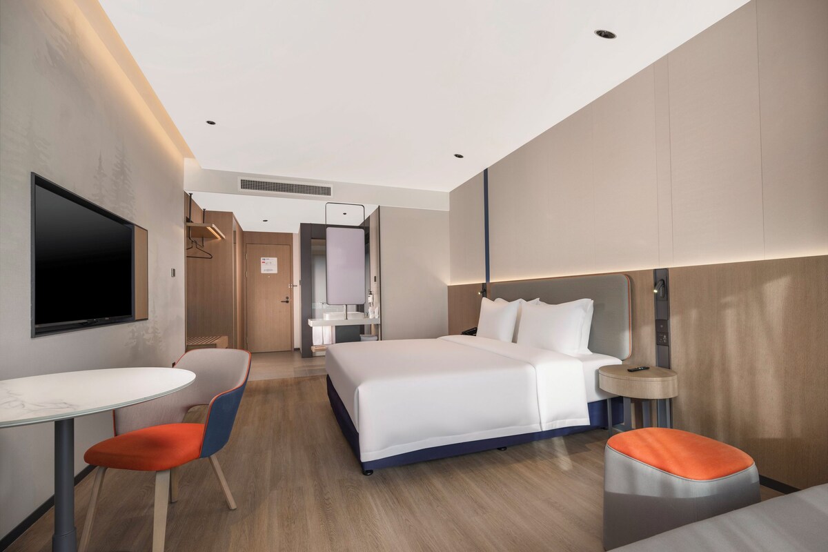 Een moderne hotelkamer met een groot bed, een bureau en een televisie.