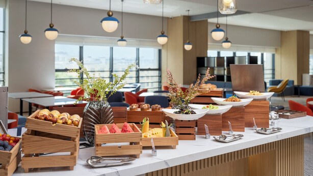 A modern kitchen with a long counter, wooden crates of fruits, and a variety of food items. - Holiday Inn Express Aksu by IHG (Aksu)