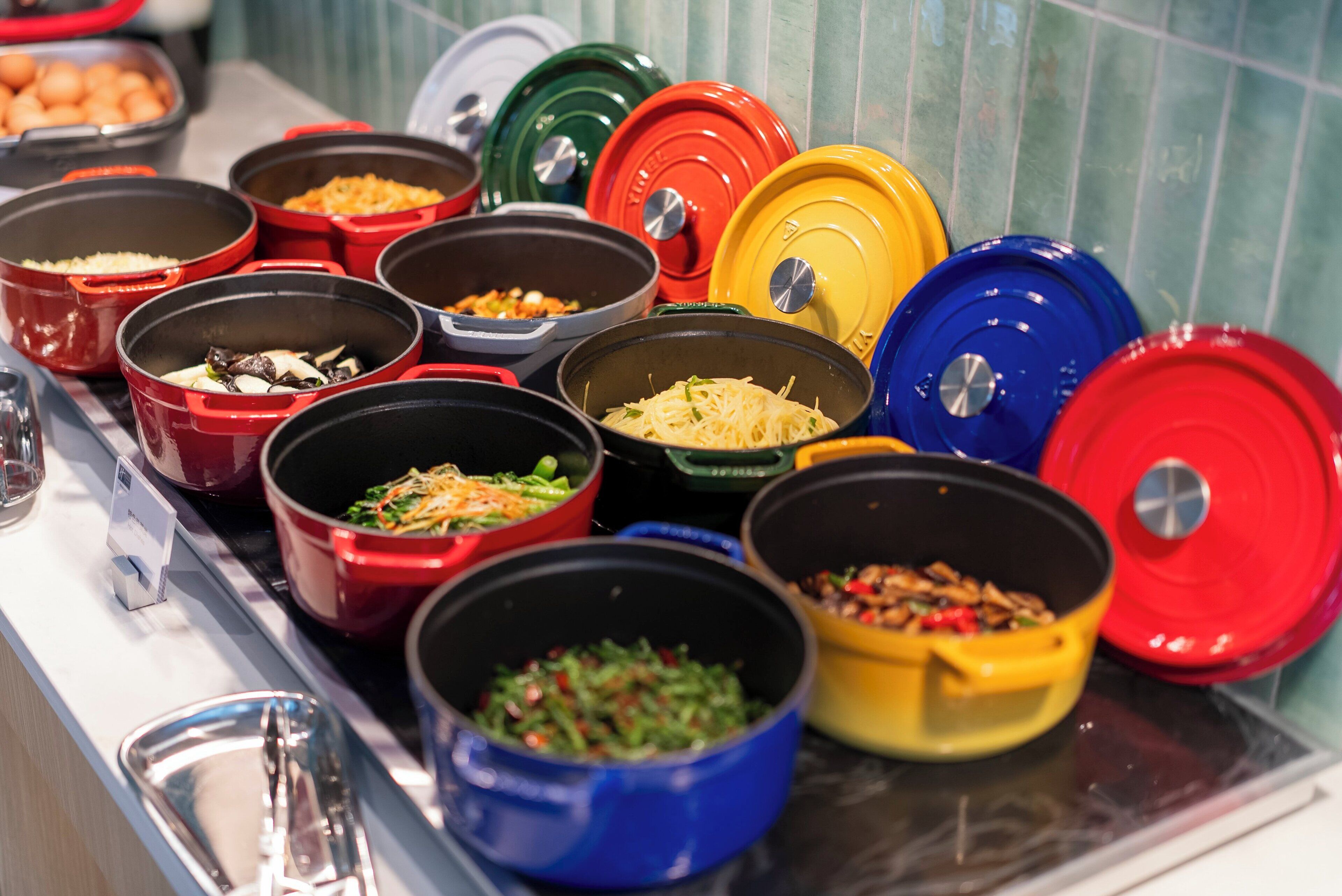 A buffet with various dishes in colorful serving containers.