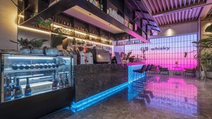 A modern bar area with a neon sign, shelves of liquor bottles, and a counter with a refrigerated display. - Holiday Inn Express Aksu by IHG (Aksu)
