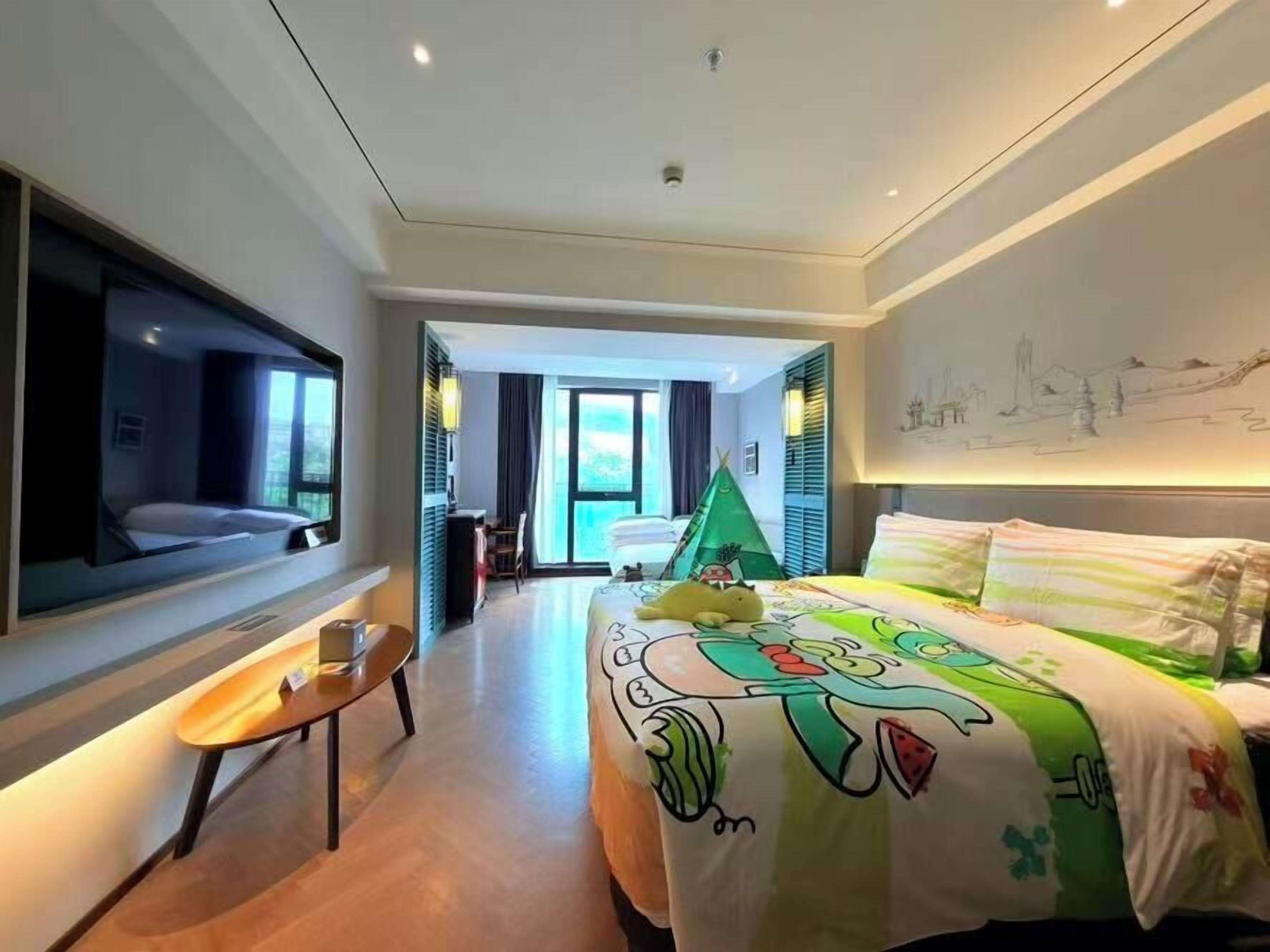 Een hotelkamer met een bed, een aan de muur bevestigde televisie, een klein tafeltje en een raam.
