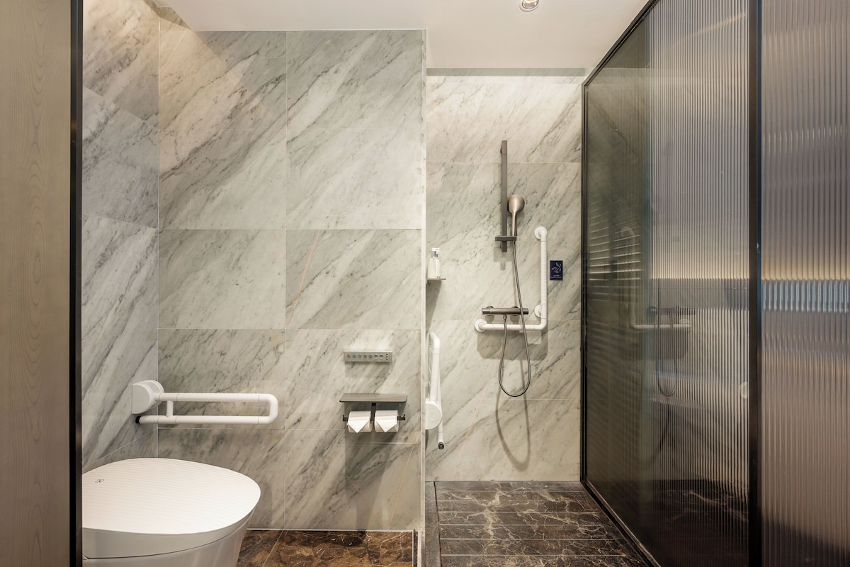 Un baño moderno con inodoro, zona de ducha y cabina de ducha con paredes de vidrio.