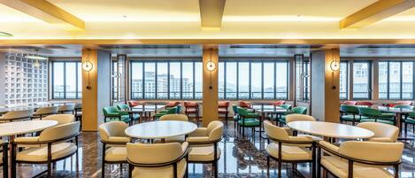 A spacious indoor area with multiple seating arrangements, large windows, and a polished marble floor.