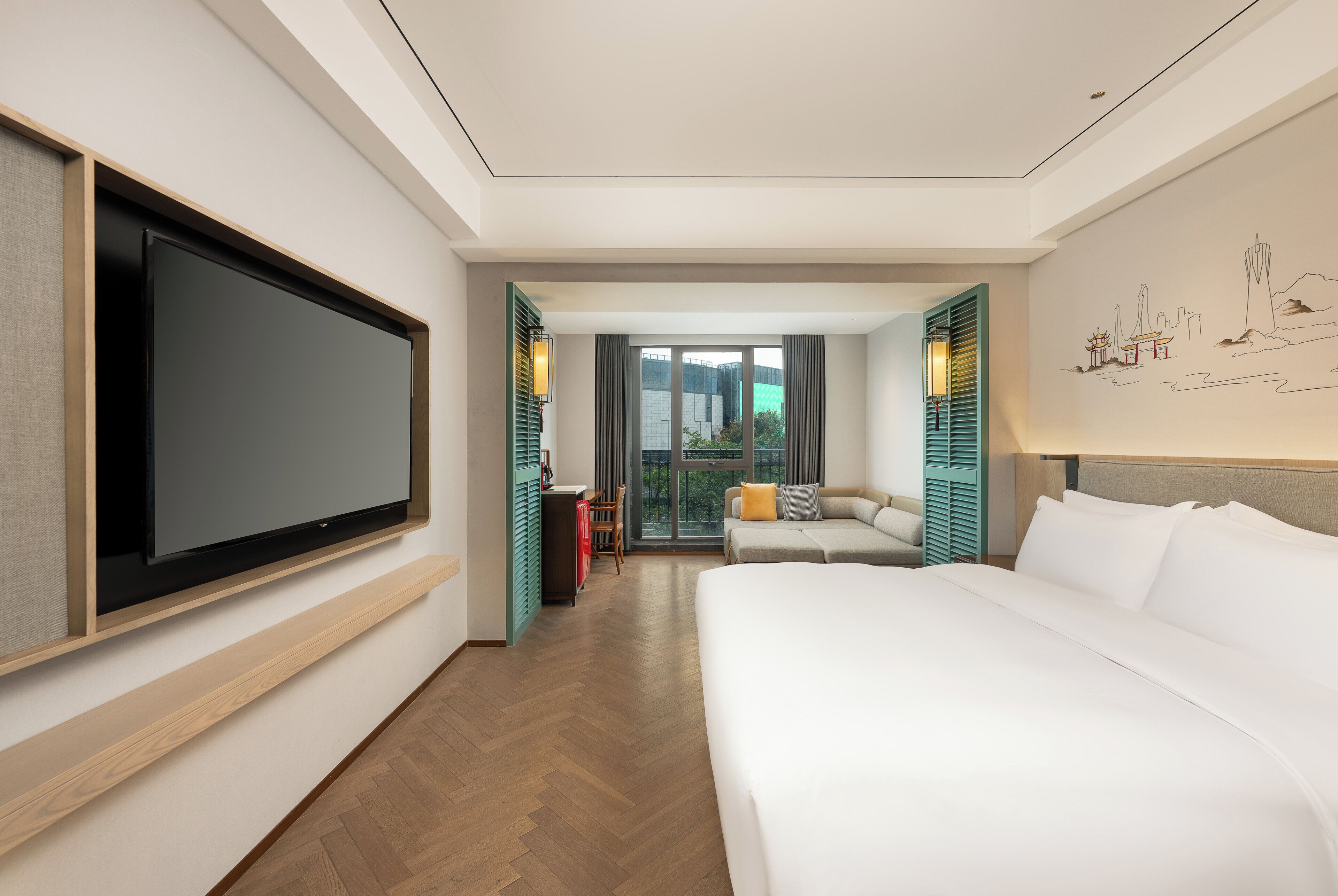 A hotel room with a large bed, a flat-screen TV mounted on the wall, a seating area with a sofa and chairs, and a view through the window.