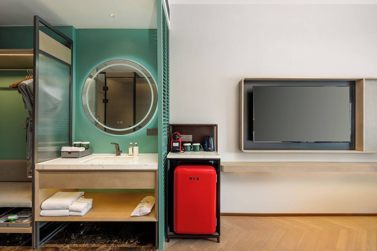 A modern bathroom with a sink, mirror, and a red appliance, likely a mini-fridge or heater.