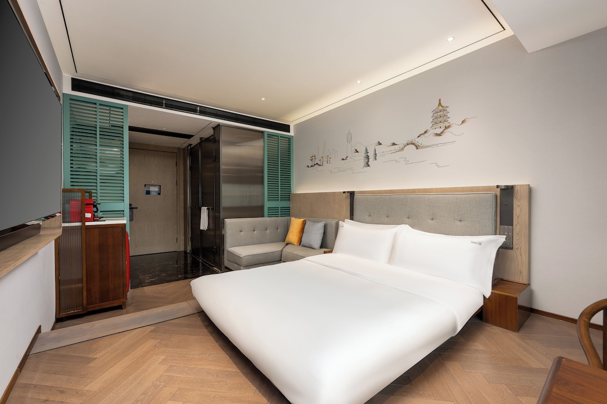 Un dormitorio moderno con una cama grande, un sofá, un escritorio y una obra de arte en la pared.
