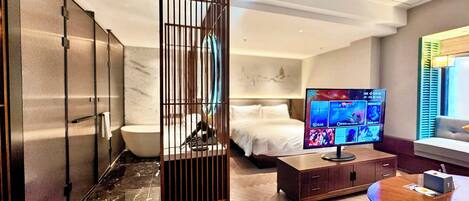 A hotel room with a bed, a television, a wooden cabinet, and a window with blinds.