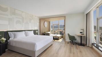 Una habitación de hotel moderna con una cama grande, un escritorio, una silla y vistas a la ciudad.