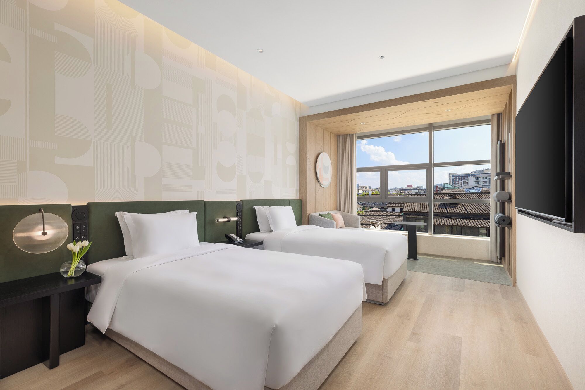 A hotel room with two beds, a large window with a city view, a flat-screen TV, and a modern design.