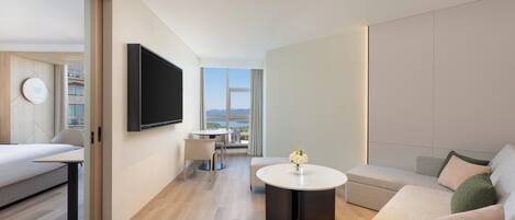 Ein modernes Hotelzimmer mit Bett, Fernseher, Essbereich und einer Couch.