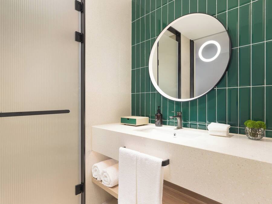 A bathroom with a mirror, sink, and towel rack.