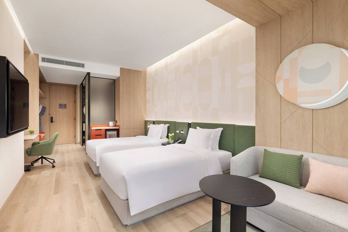 Una habitación de hotel con dos camas, un sofá, un televisor y un escritorio con una silla.